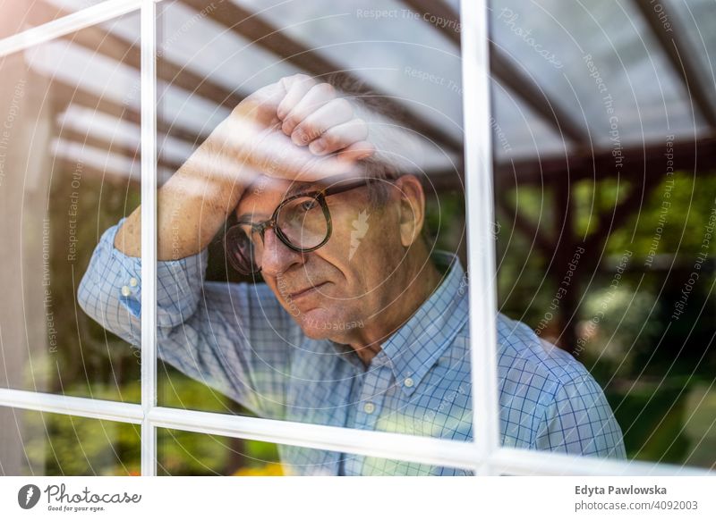 Senior man looking out of window at home senior elderly grandfather old pensioner retired retirement aged mature house male people lifestyle domestic life