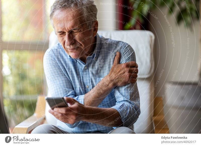 Senior man experiencing pain while using a smartphone at home senior elderly grandfather old pensioner retired retirement aged mature house male people