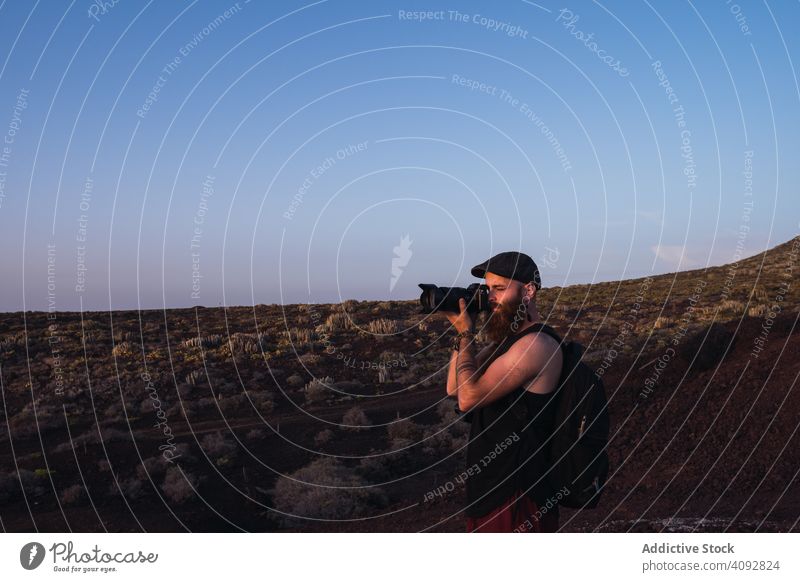 Photographer in desert landscape man taking photo backpack travel photography dusk camera remote sky twilight explore professional job spain tenerife tourism