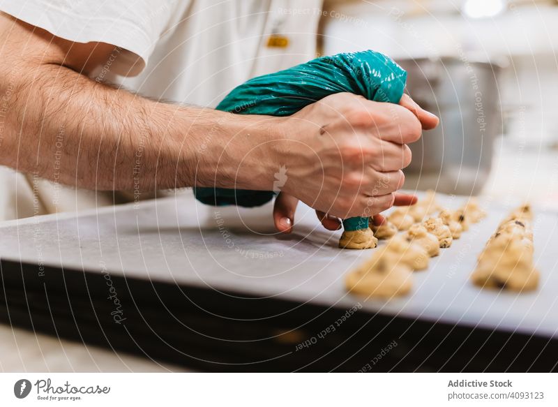 Crop baker squeezing dough on tray confectioner bakery squeeze cookie work kitchen preparation professional cuisine food paper pastry restaurant sweet chef