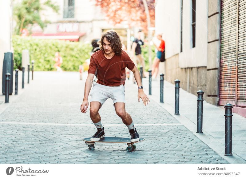 Confident man riding longboard across city street ride urban freestyle trick focused casual cool confident sunny summer pavement balance young adult skater