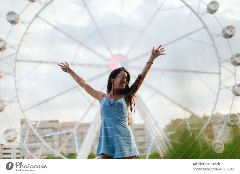 Dreamy woman resting by Ferris wheel in amusement park dreamy summer fairground sundress ferris wheel relaxed calm entertainment wistful long hair attractive