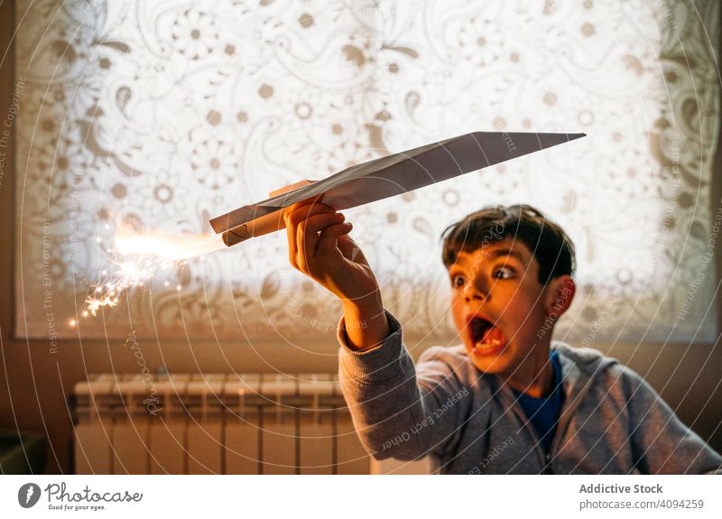 Shocked child having fun with toy plane boy play shock paper airplane amused petard room happy childhood leisure game joy cute cheerful sit rest relax vacation