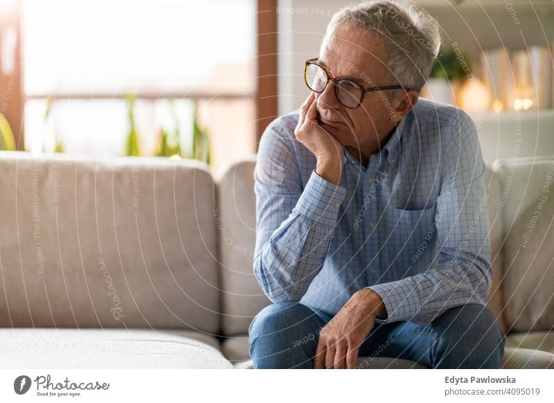 Worried senior man sitting alone in his home people one person mature pensioners retiree retired retirement old elderly gray hair caucasian adult lifestyle male