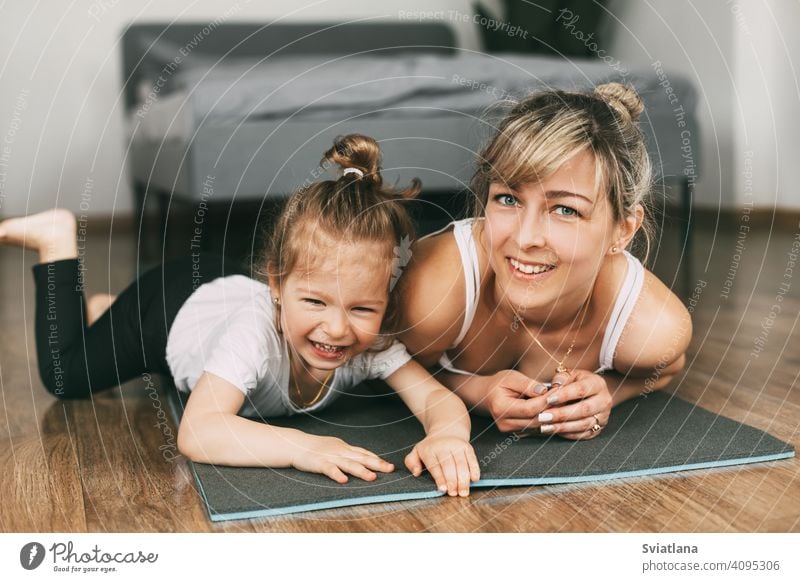 A little cute girl practices a yoga pose indoors. The child does yoga and  gymnastic exercises. Stock Photo