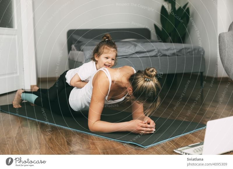 A young sports mom and a girl together do exercises at home. Healthy development of parents and children, healthy lifestyle woman fitness mat beautiful little