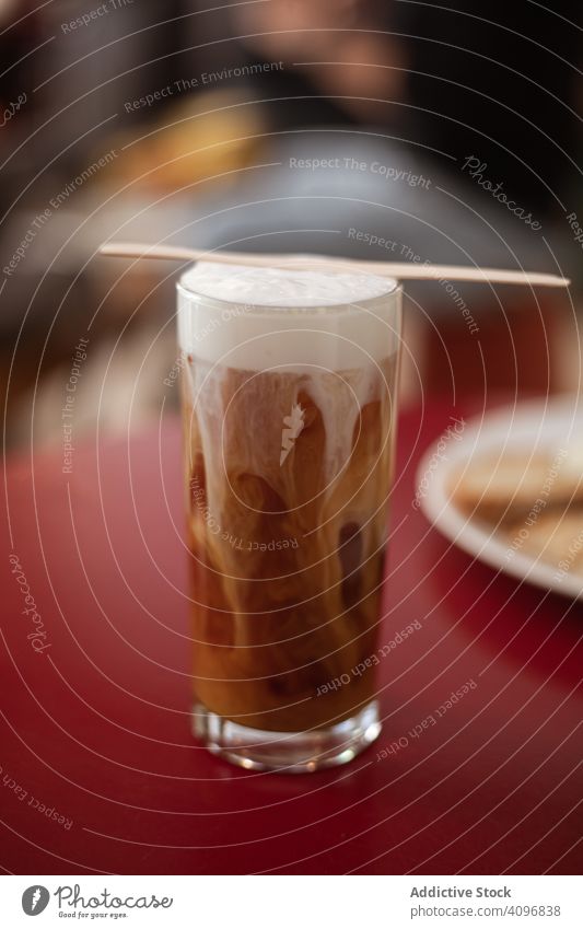 Coffee drink with foam in tall glass beverage coffee brew caffeine brown served table red bright mix refreshment celebration aroma full alcoholic nonalcoholic