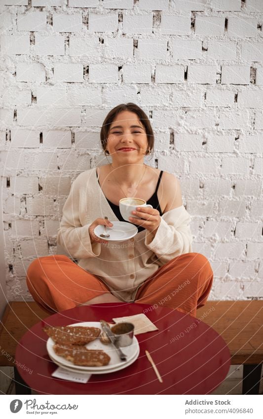 Peaceful woman drinking coffee while resting at home peaceful comfort relaxed domestic mug kitchen table food sit hot drink morning breakfast apartment young
