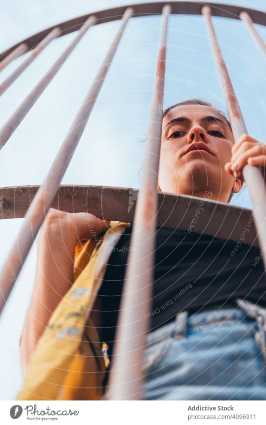 Thoughtful female leaning on metal fence woman sky summer urban cage behind capture view thoughtful freedom modern upset alone hide standing sensual clear young