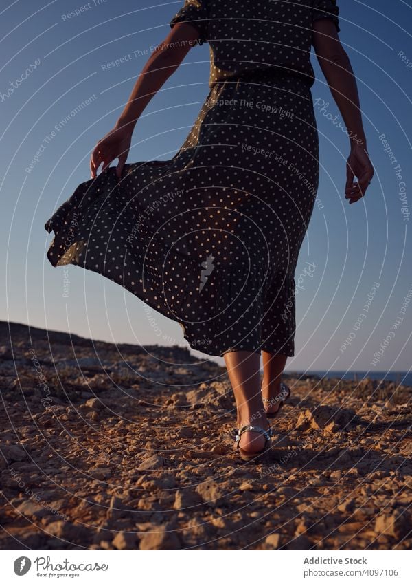 Woman walking on beach while wind waving dress - a Royalty Free