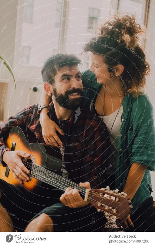 Cheerful couple playing guitar at home cheerful laugh fun casual domestic hobby music tender musician happy guitarist adult lifestyle together smile relaxing