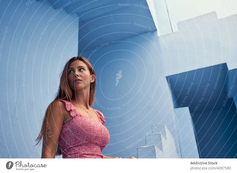 Woman walking upstairs on modern blue building woman long hair elegant construction structure geometric architecture urban facade downtown center wall abstract
