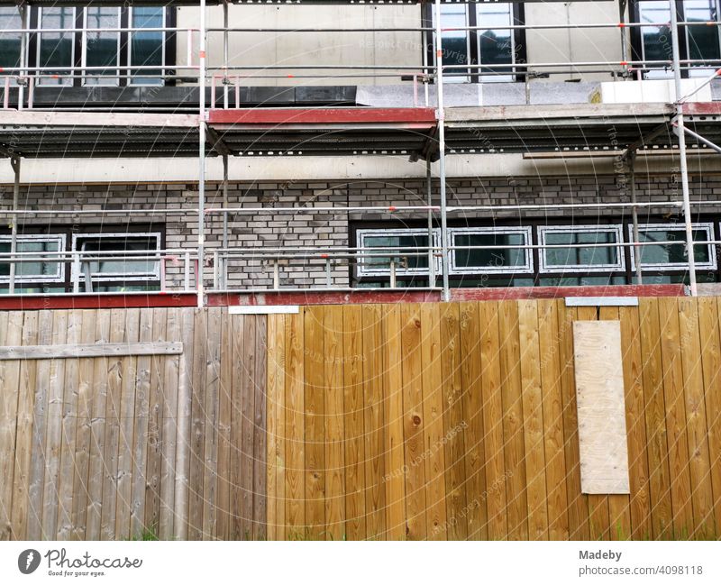 Wooden construction fence in front of the new building of a residential house with scaffolding at the former harbour in Offenbach am Main in Hesse