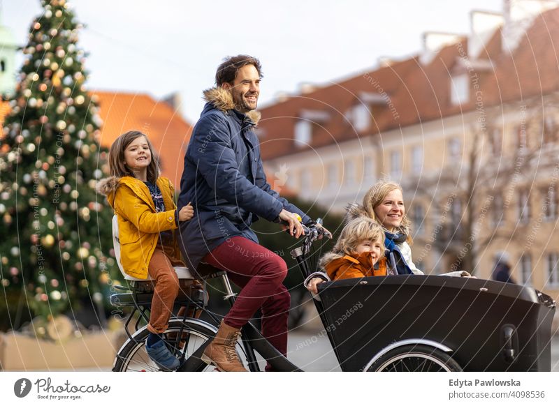 Young family riding in a cargo bicycle during Christmas cargo bike cycling transport tricycle healthy active biking modern sustainable transport ecological