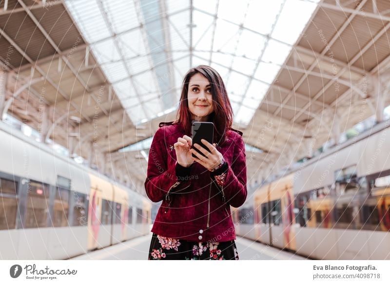 beautiful caucasian woman in train station ready to travel using mobile phone. Travel and lifestyle concept technology smart phone internet device connections
