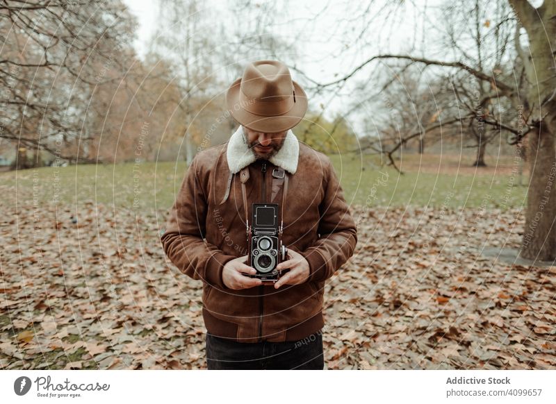 Male photographer standing in autumn park man photo camera retro london casual peaceful adult male great britain england vintage leaf fall season tree shoot