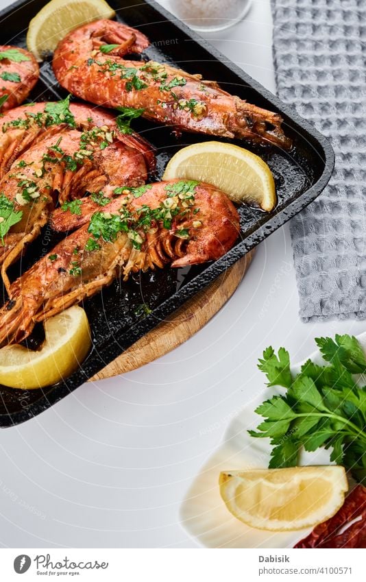 Grilled large queen shrimps with lemon and spices on the grill pan prawns seafood red background dark black dish tiger cooked crayfish eating gourmet healthy