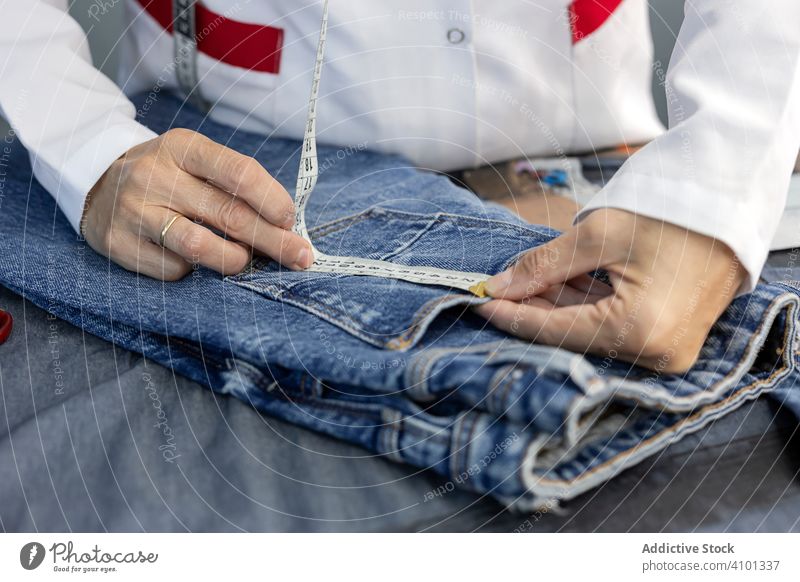 Working woman in textile factory checking industry clothing manufacturing worker machine sewing hands fabric pants blue jeans occupation industrial production