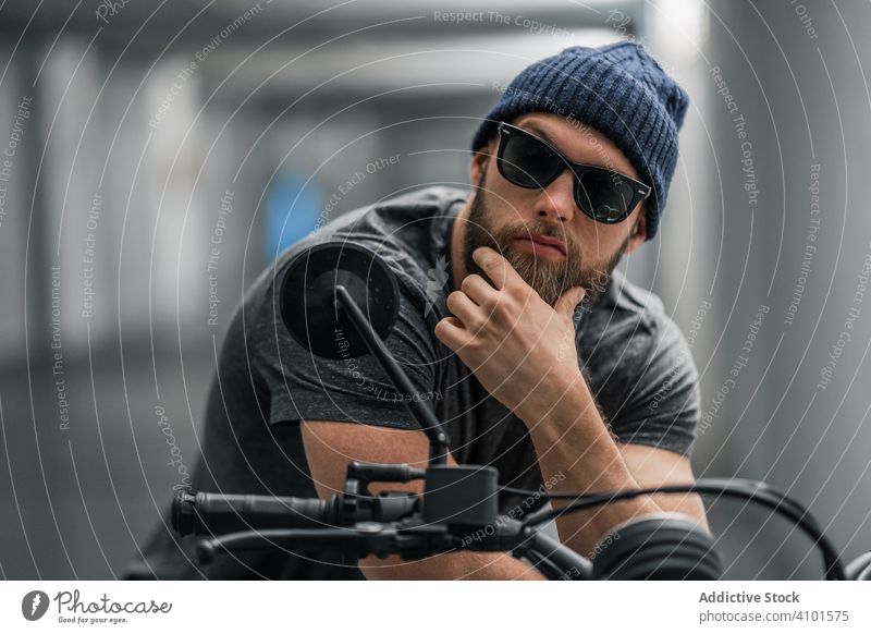 Bearded biker in garage hallway motorcycle man modern sit confident bearded transport ride male vehicle motorbike city urban corridor contemporary facility