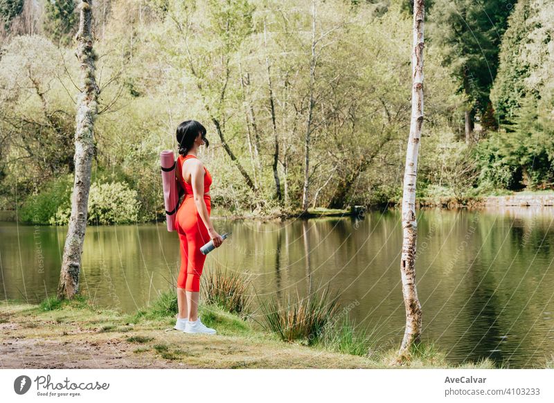 Young woman in fitness clothes at the park with a yoga mat and a bottle of water with copy space forestry people exercising horizontal training gym happiness