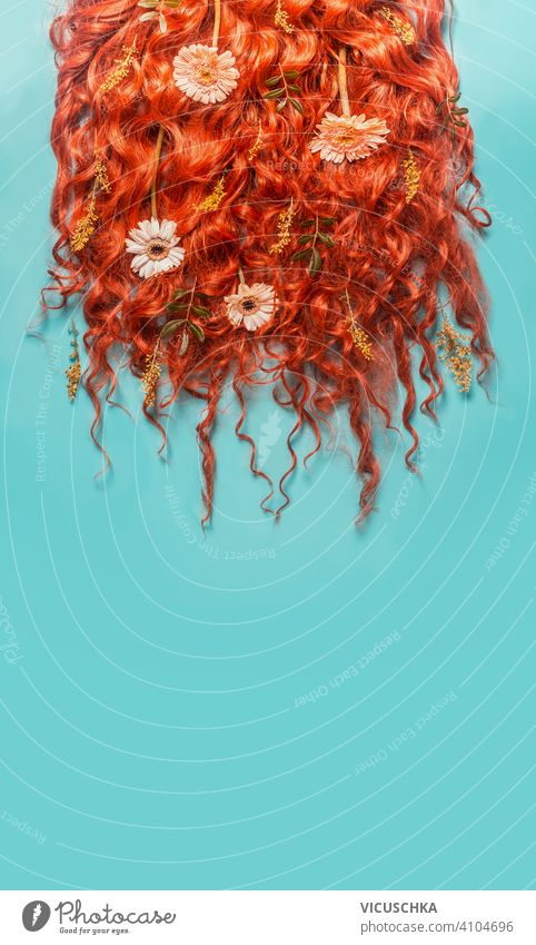Red ginger curved hair background with flowers on turquoise blue background. Beauty and hair styling concept. red beauty green leaves cosmetic product bottle