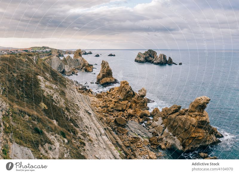 Stone peaks and seashore and foamy waves under cloudy sky scenery ocean water nature landscape travel scenic cantabria santander pielagos spain coast