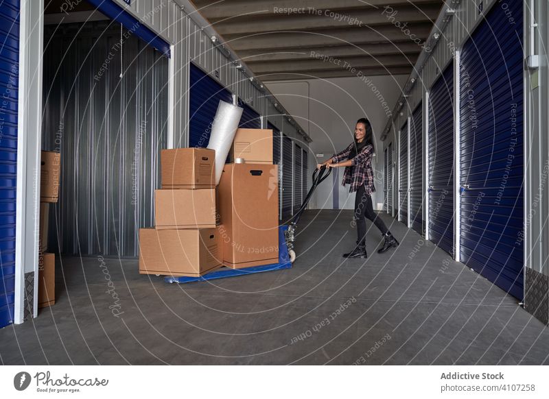 Woman moving wheelbarrow with boxes woman package warehouse courier packing cargo distribution storage delivery transportation move work mortgage relocating