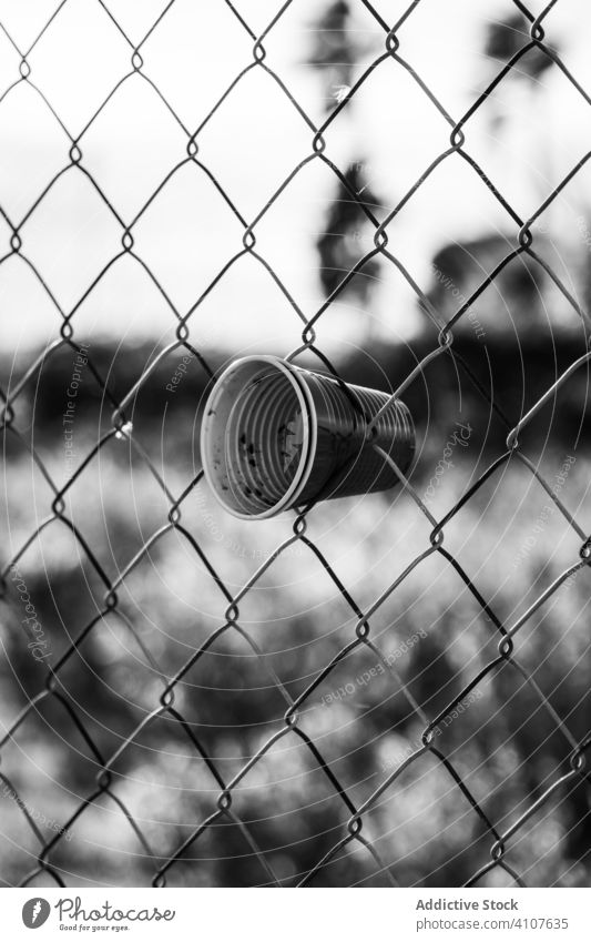 Plastic cups in security metal fence wall glass plastic trash chain link used protection safety construction structure steel architecture pattern abstract