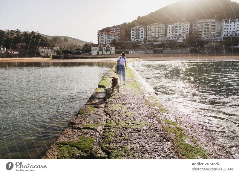 Woman with dog walking on stone pier woman building water sea together pet coast animal lifestyle female young casual friendship spain lekeitio basque country