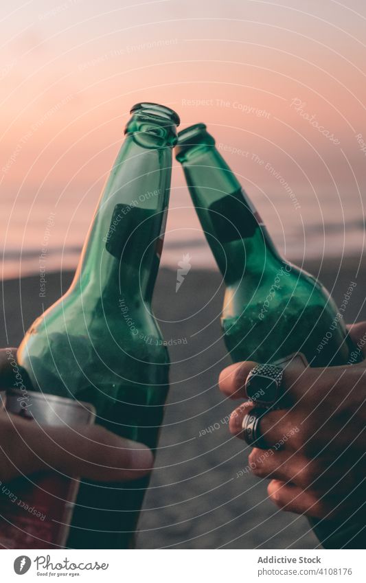 Friends toasting with beer on sunset beach bottle friend summer sea sky hand clink together relax enjoy drink alcohol beverage weekend evening vacation coast