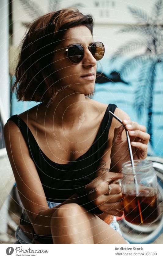 Joyful female traveler in sunglasses drinking cocktail woman resort tropical summer lounge cheerful exotic tourism relax smile rest laugh enjoy beverage