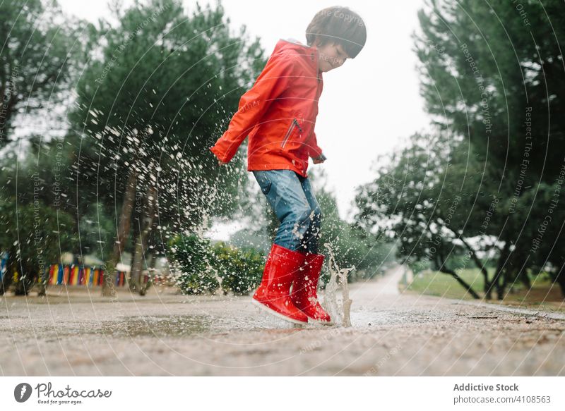 Little boy wearing yellow rubber boots walking on rainy summer day in small  town. Child having fun. Outdoors games for children in rain. - a Royalty Free  Stock Photo from Photocase