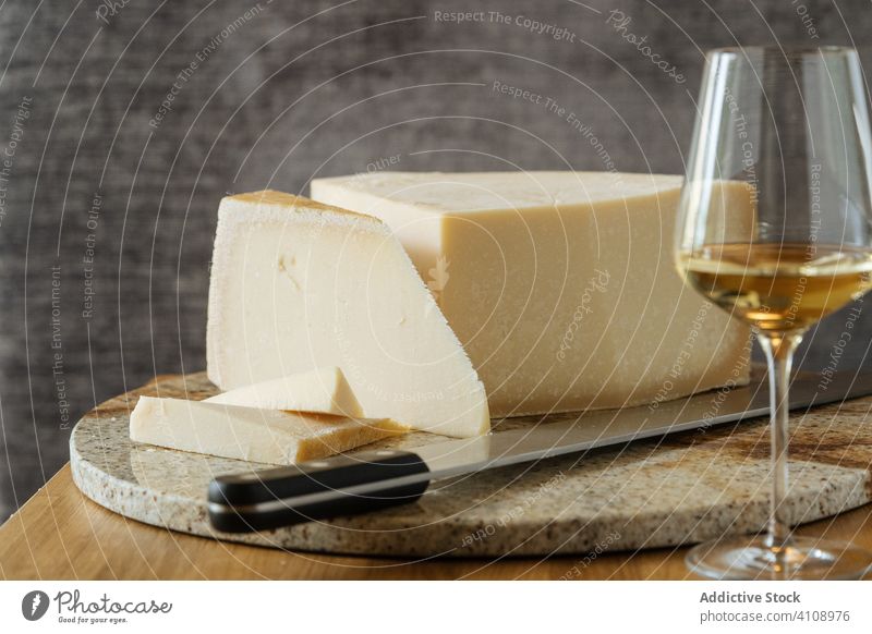 Cheese on cutting board and wine on table cheese knife beverage glass gourmet alcohol delicious tasty restaurant drink food fresh utensil portion slice luxury