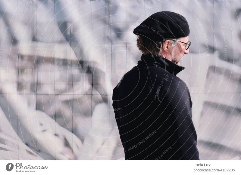 Man with cap in front of construction fence, grey in sunlight Graffiti Wall (building) Gray Gray-haired Cap Town Meditative from behind Doomed Gloomy