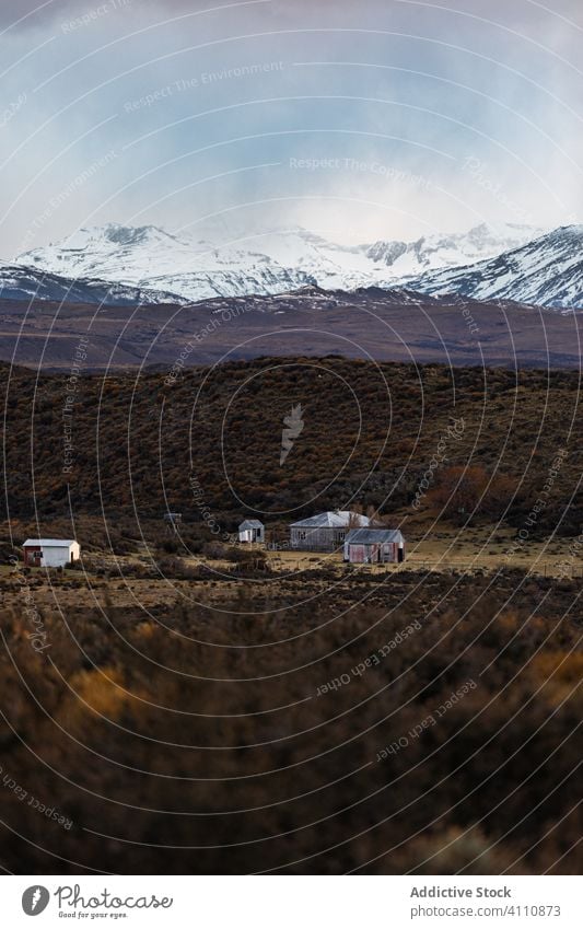 Small settlement on plain against mountain ridges in overcast weather house horizon foothill travel top country solitude highland countryside rural scenic