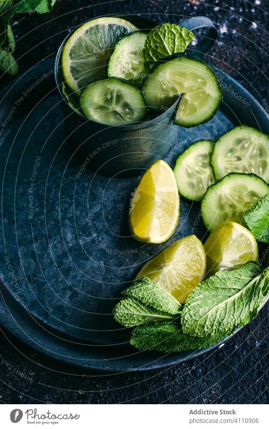 Cucumber detox drink with mint and lime cucumber ingredient table lemon cold mug tray dark fresh healthy natural citrus fruit composition cup arrangement