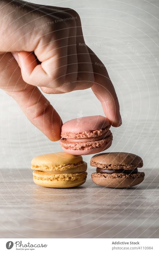 Crop hand placing macaroons on the table man finger pile biscuit fresh tasty cookie bright ingredient food baked sweet snack cake colourful kitchen sugar circle