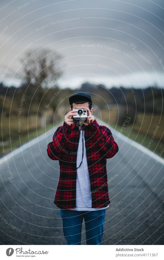 Anonymous man with photo camera in countryside road nature casual male shoot hobby tourism travel trip adventure young equipment journey creative instant camera