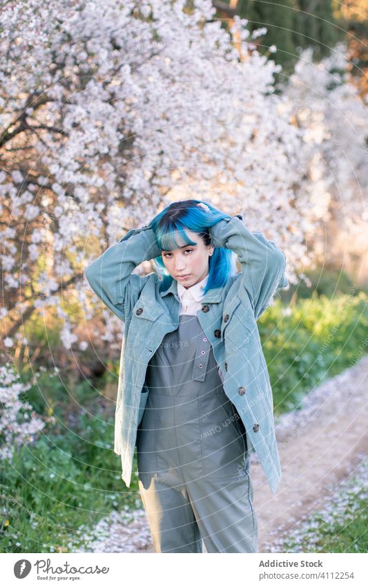 Trendy woman in blooming garden spring teen dyed hair flower style trendy modern young blue hair blossom tree female nature floral beautiful season fresh park