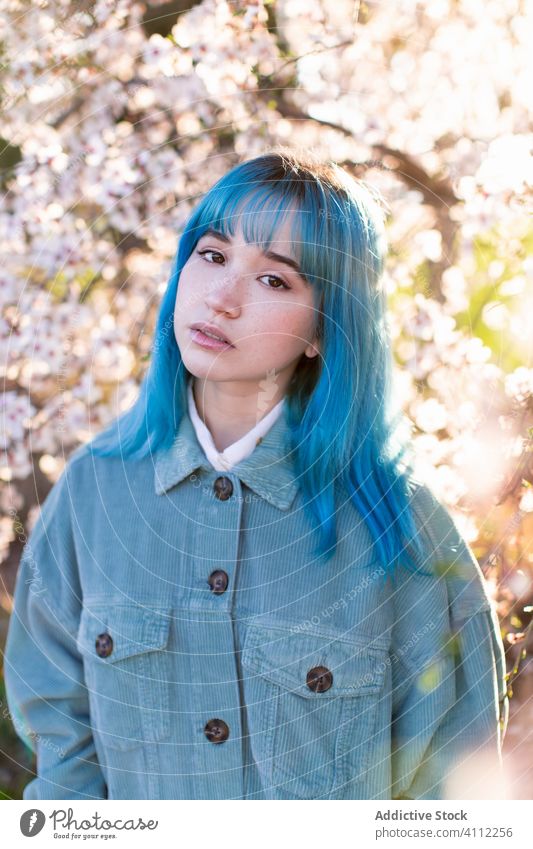 Trendy woman in blooming garden spring teen dyed hair flower style trendy modern young blue hair blossom tree female nature floral beautiful season fresh park