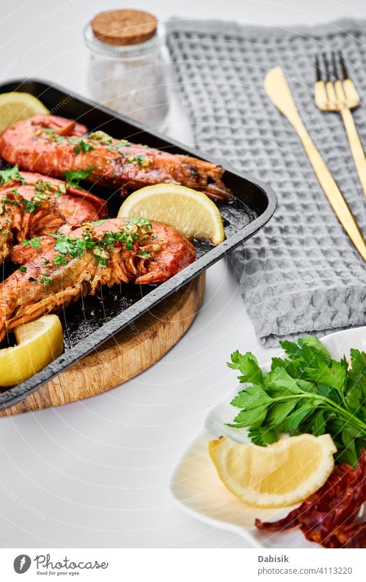 Grilled large queen shrimps with lemon and spices on the grill pan prawns seafood red background dark black shellfish dish tiger cooked crayfish eating gourmet