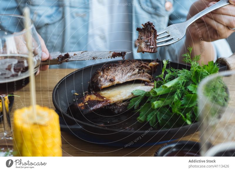 Person eating grilled meat in restaurant corn steak person herb green roast tasty bone barbecue rustic wooden food meal delicious cook vegetable dinner dish