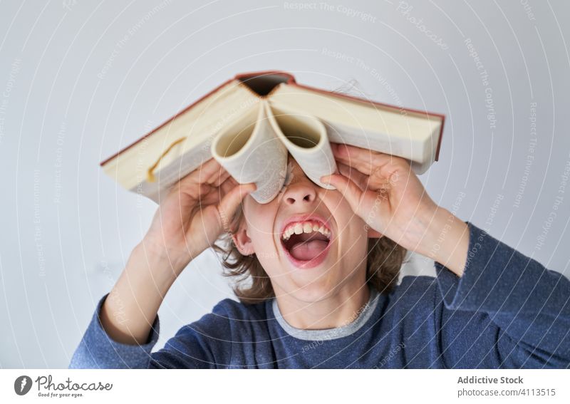 blond boy in pajamas using a book as binoculars exploration finding future discovery education explorer child life looking adventure little research searching