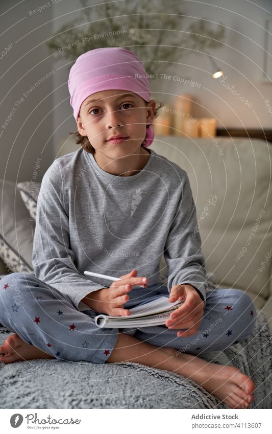 Focused little boy writing notes on bed write cancer diagnosis child home therapy male childhood faithful relax optimism awareness room pajama remission sick