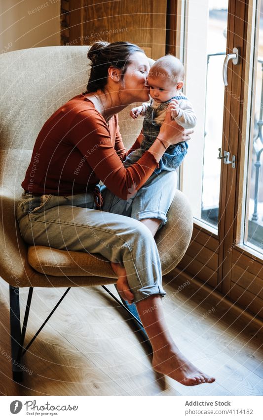 Mother with baby sitting near window mother baby talk chair home cozy comfort casual happy cute love tender woman infant adorable barefoot child kid smile