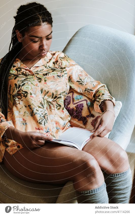 Ethnic woman with book resting at home read casual chair calm young cozy ethnic female free time relax lifestyle sit literature comfort novel peaceful hobby