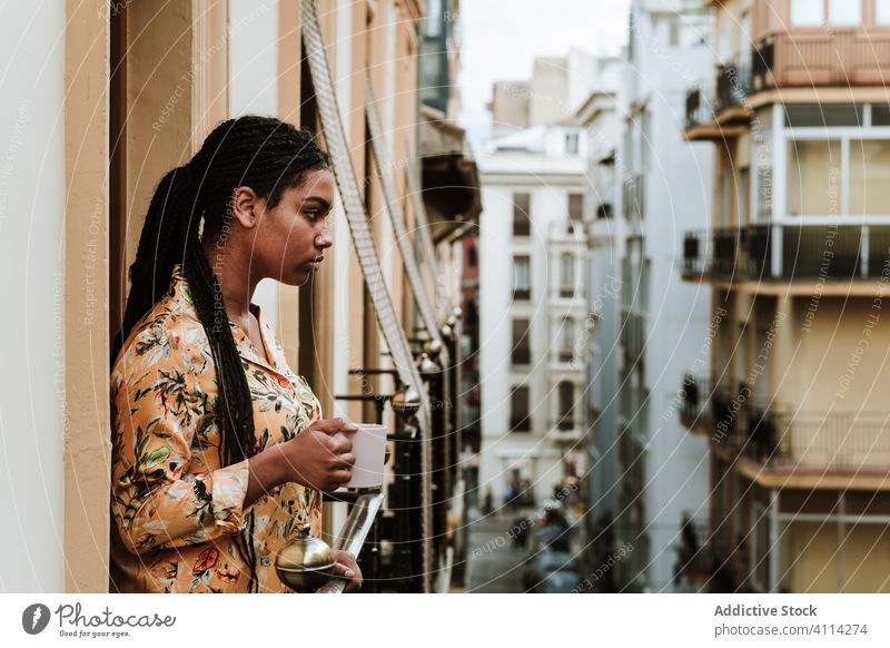 Young woman with cup of coffee standing on balcony calm drink casual home tranquil thoughtful relax young african american black ethnic female house city