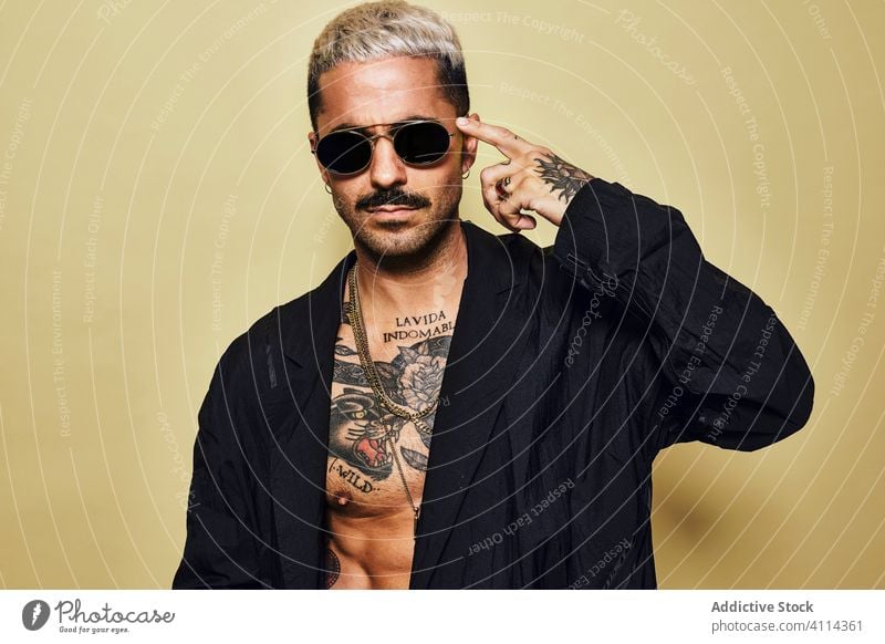 Provocative shirtless man in black coat and sunglasses macho cool trendy brutal tattoo style fashion unshaven model personality muscular beard male ethnic