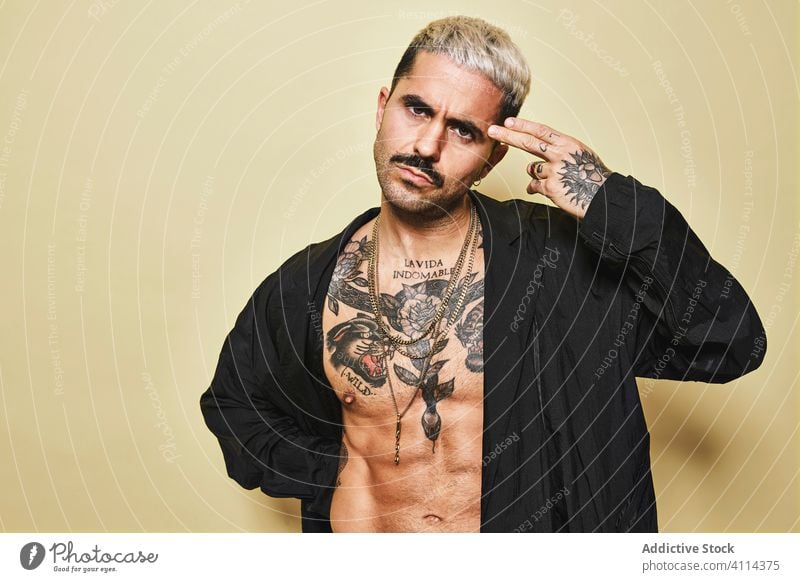 Aggressive muscular male model with tattoos man style trendy brutal fashion provocative coat arrogant black beard ethnic modern outfit serious appearance