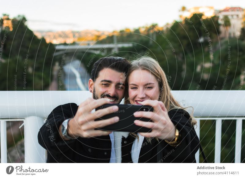 Happy multiethnic couple taking selfie in city smartphone happy together bridge young street urban lifestyle device gadget mobile relationship multiracial